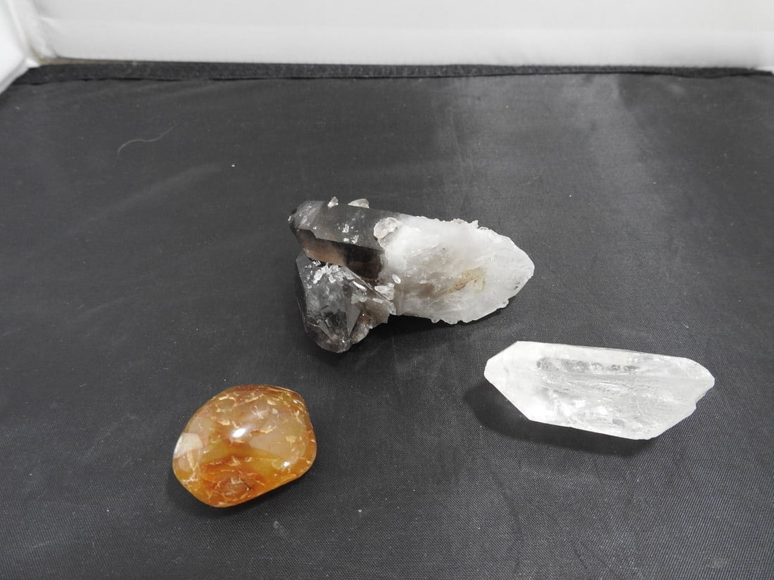 Lot of Three Assorted Crystals and Minerals: Lot of three assorted crystals/minerals including a clear crystal point, an orange polished stone, and a rough crystal/mineral specimen on matrix as shown. Approx. 2.5 x 3.5 x 2.5 in.