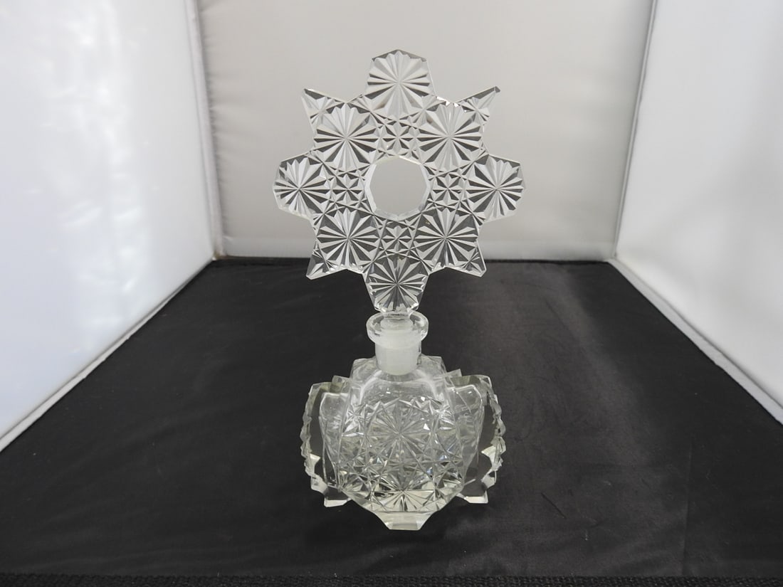 Cut Crystal Covered Perfume Bottle: Cut crystal covered perfume bottle with faceted body and decorative stopper. Minimal chipping noted. Approx. 8 x 4.5 x 2.75 in.