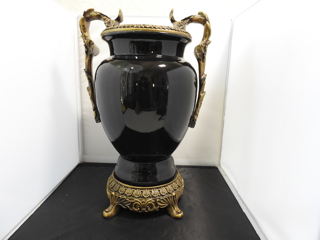 French Empire Style Black Urn Vase: French Empire style black urn vase with ornate gold-tone resin/metal-look mounts, handles, and footed base. Ceramic and resin construction; lightweight mass-produced decorative piece. Approx. 16 x 11