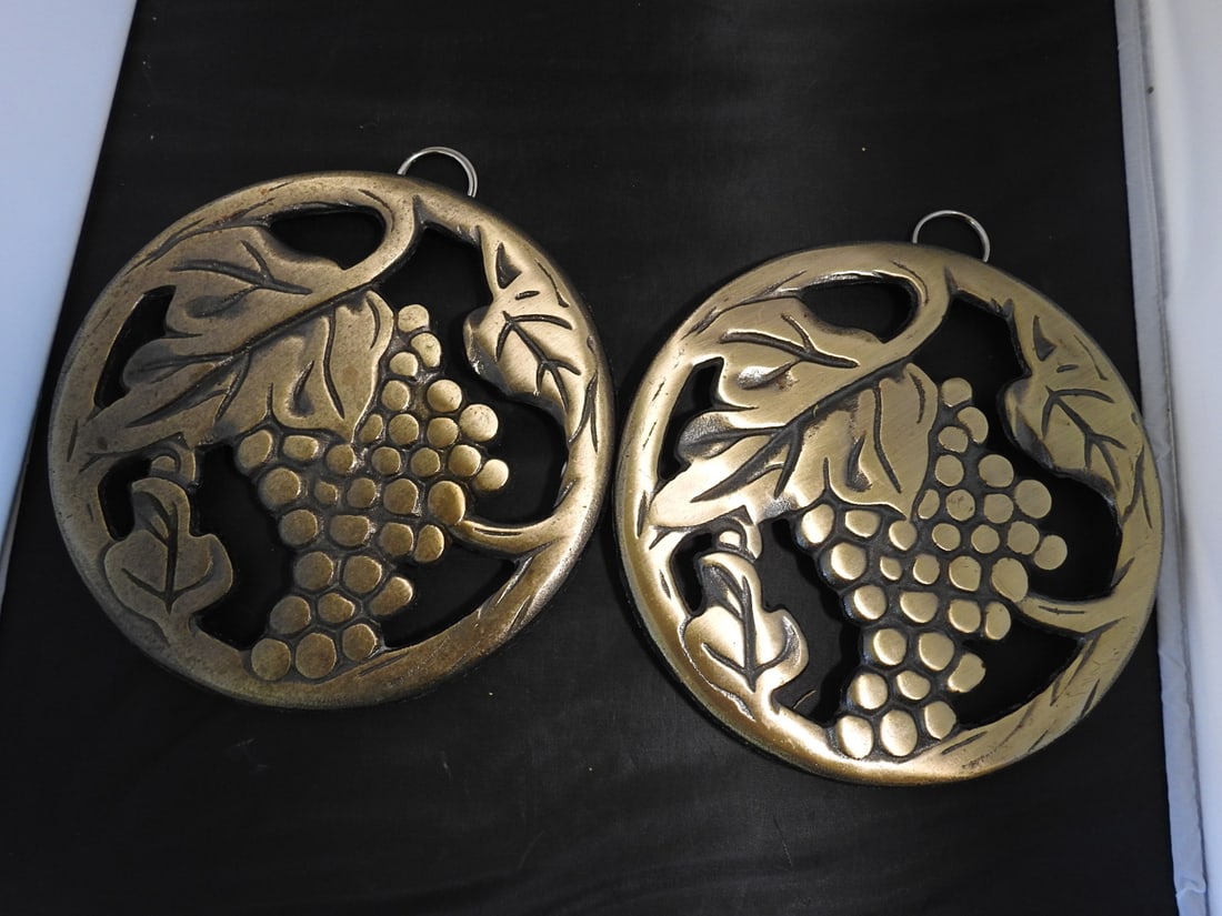 Pair of Cast Brass Grape Design Trivets: Set of two cast brass trivets with grape and leaf design. Made in China; copyright 2009. Approx. 3 x 9 x 9 in.
