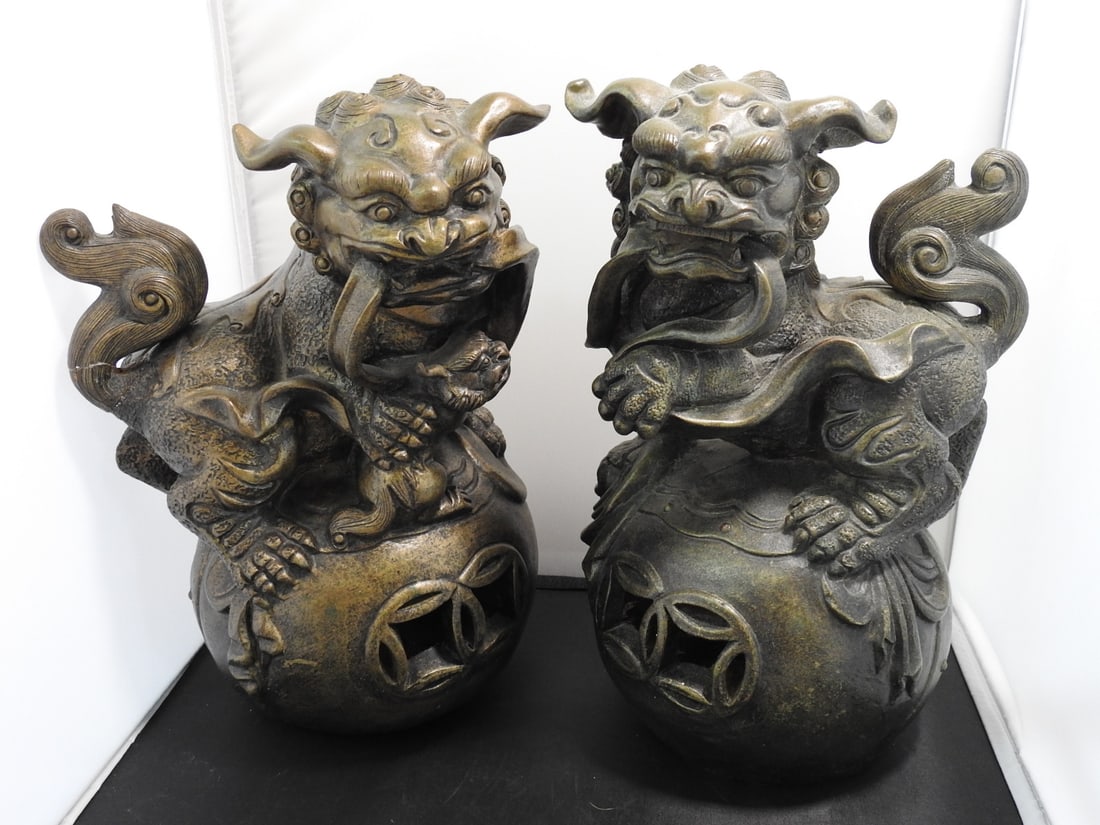 Pair of Faux Bronze Chinese Foo Dog Guardian Lion Figures: Pair of faux bronze Chinese foo dog / guardian lion figures with bronze-tone terra cotta construction, raised details, openwork bases, and opposing male/female forms. Approx. 14 x 10 x 15 in. measured