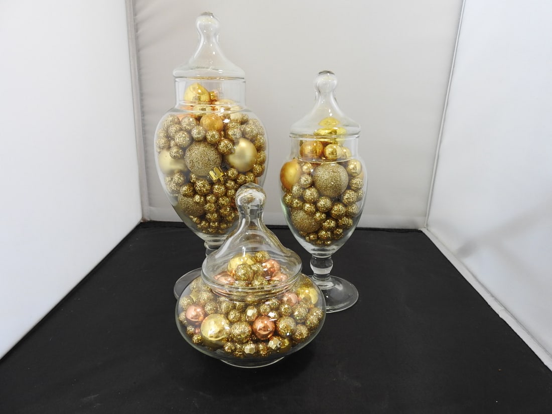 Set of 3 Glass Apothecary Candy Jars with Gold Balls: Set of three glass apothecary / candy jars filled with decorative gold balls. Measured as a set. Approx. 11 x 7.5 x 7 in.