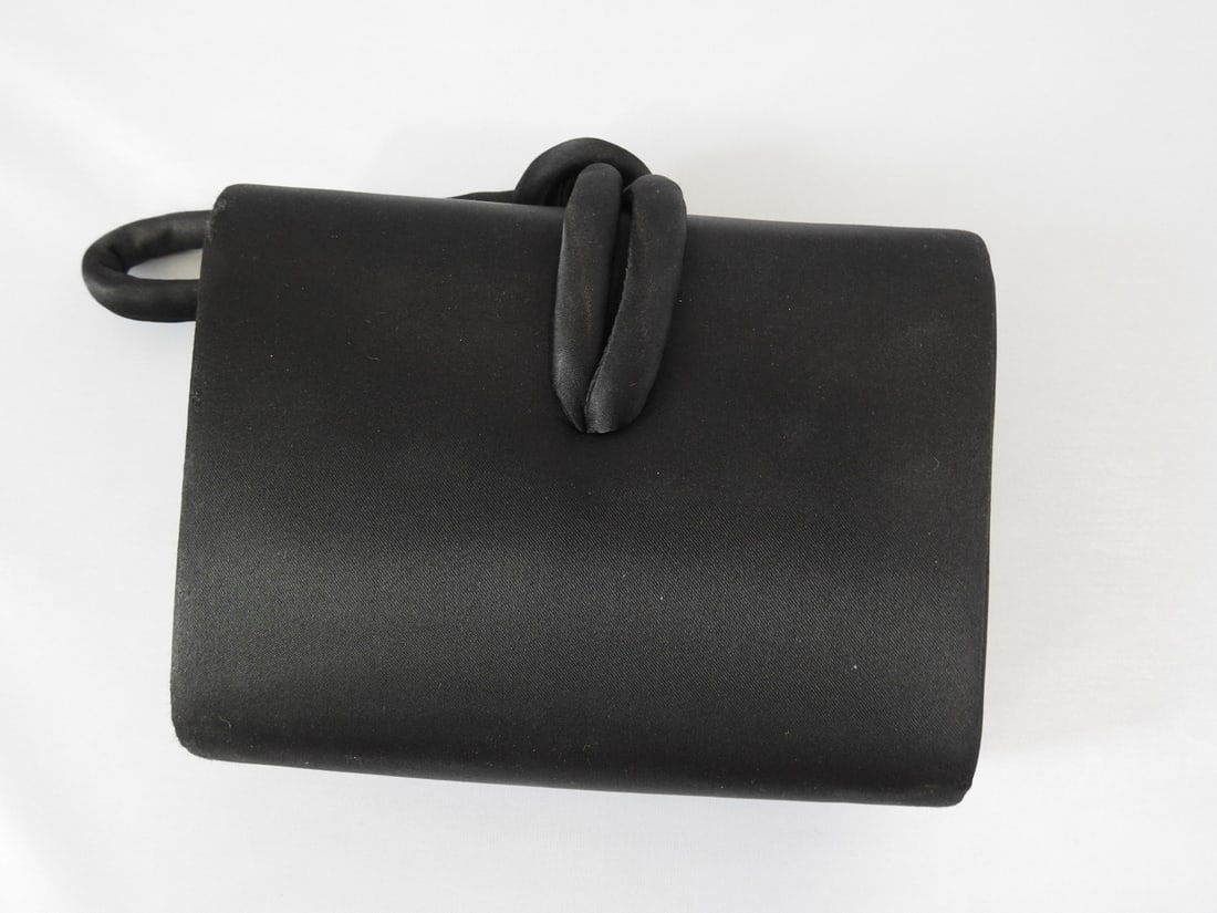 Valerie Stevens Black Satin Clutch Bag: Valerie Stevens black satin clutch bag with sculptural handle. Appears unused. Approx. 6 x 6.25 x 2.25 in.