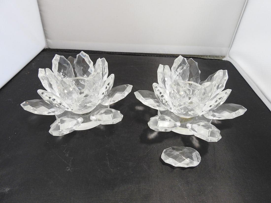 Set of 2 Lead Crystal Lotus Flower Candle Holders: Set of two lead crystal lotus flower candle holders with layered petal design. One petal is unglued and can be reattached; small chip noted. Approx. 3.5 x 10.5 x 5.5 in.