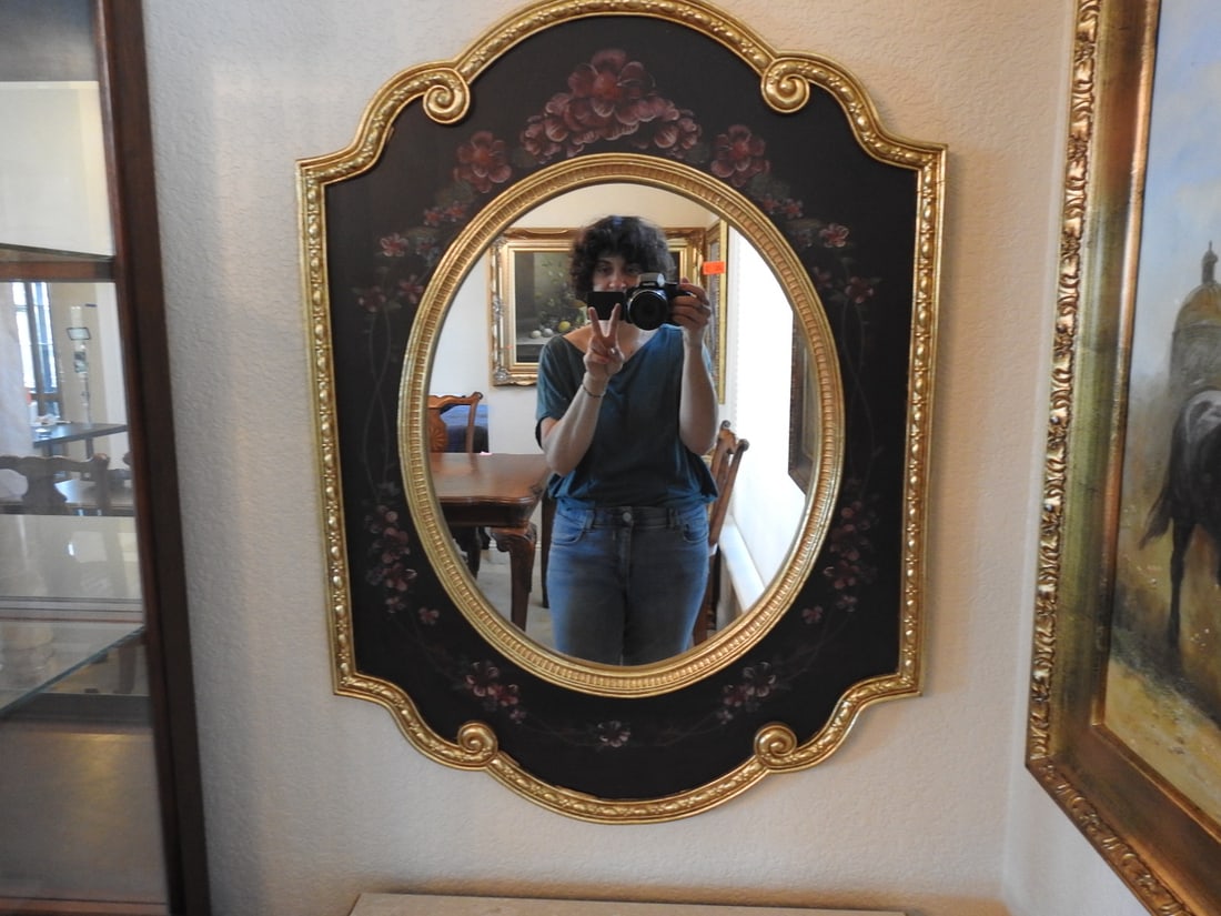 Baroque Style Oval Wall Mirror with Gilt Floral Detail: Baroque style oval wall mirror with dark backing panel, floral gilt decoration, and ornate framed edge. Approx. 33 x 24.5 x 1 in.