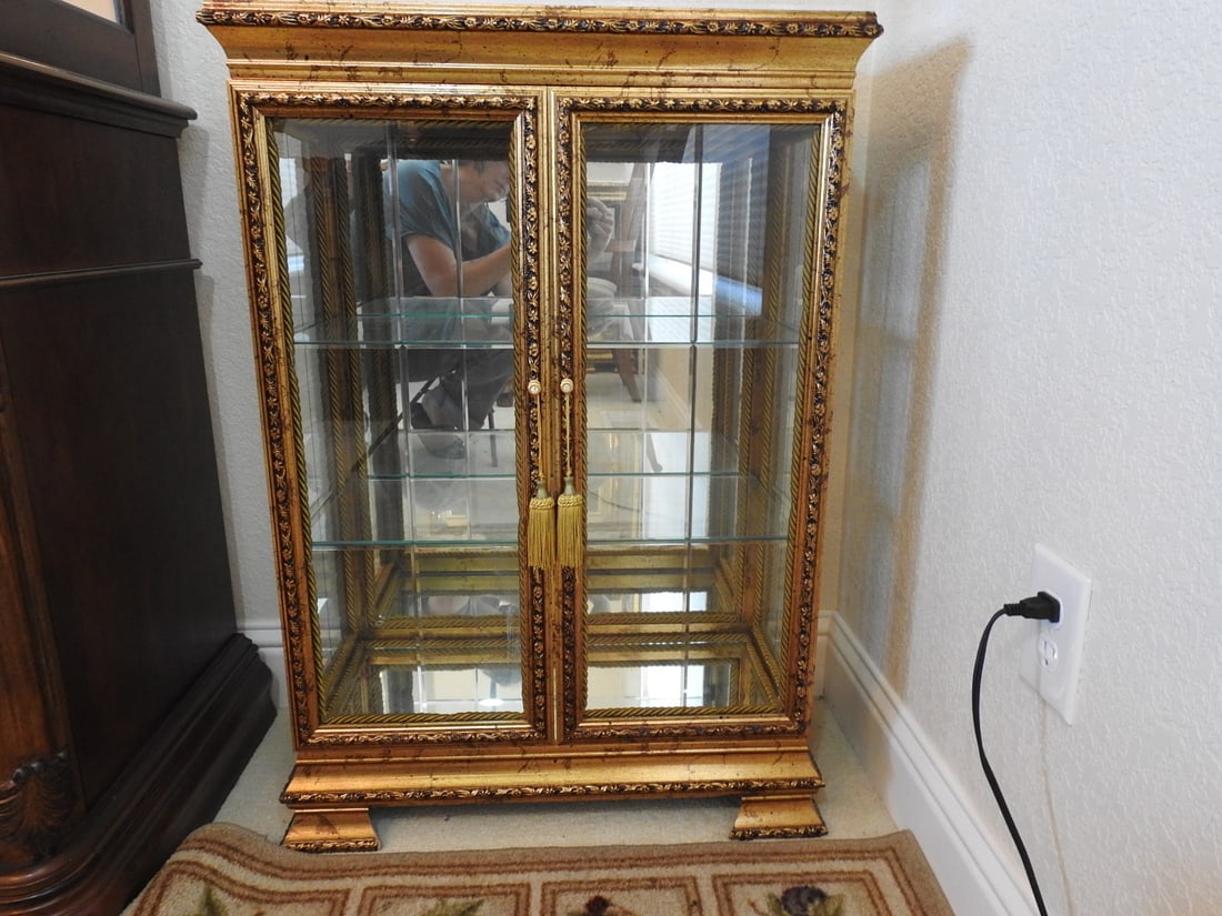Venetian Rococo Revival Display Cabinet: Venetian Rococo Revival style display cabinet with gold gilt wood frame, mirror backing, glass shelving, beveled/edge glass doors, and faux marble top. Approx. 34.5 x 24 x 12 in.