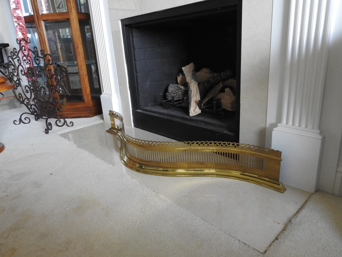 Brass Fireplace Fender by Colonial Williamsburg / VA Metalcrafters: Brass fireplace fender by Colonial Williamsburg / Virginia Metalcrafters, with curved guard form and decorative metalwork. Approx. 7.25 x 48 x 11 in.