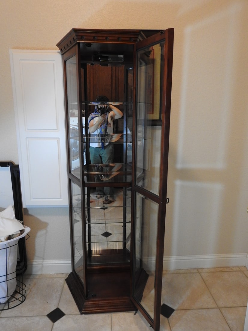 Cherry Finish Lighted Curio Cabinet: Cherry finish lighted curio cabinet with pebbled/tempered glass, mirrored backing, glass shelves, and half-hexagon form. Approx. 74.5 x 25 x 14.5 in.
