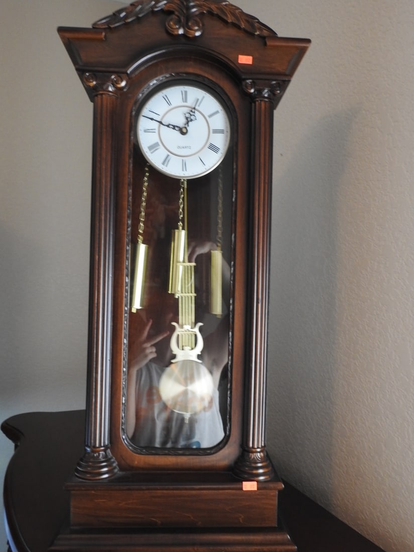 Neoclassical Style Carved Walnut Wall Clock: Neoclassical style carved walnut wall clock with battery-operated movement and sliding back opening. Approx. 33.5 x 16 x 6 in.