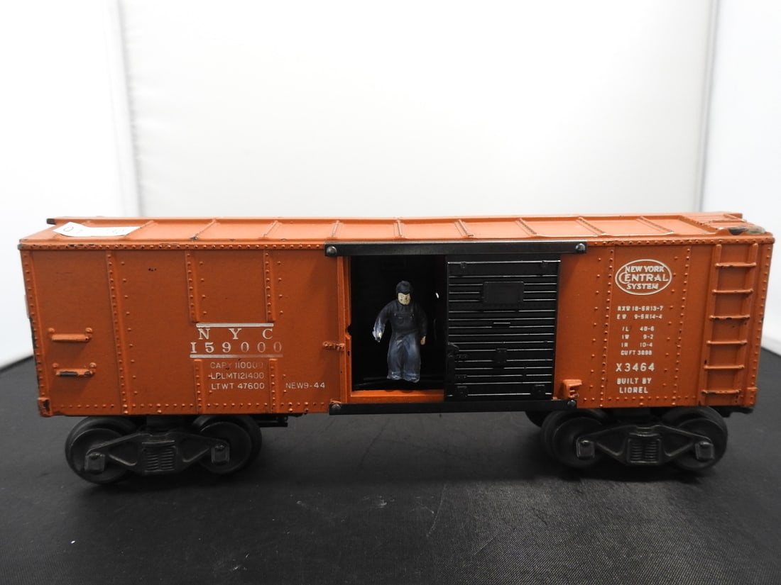 Lionel X3464 New York Central Operating Boxcar: Lionel O gauge X3464 New York Central operating boxcar with orange body, black sliding door, NYC 159000 markings, and built 9-44 railroad lettering. Postwar-era, 1950s-style operating boxcar;