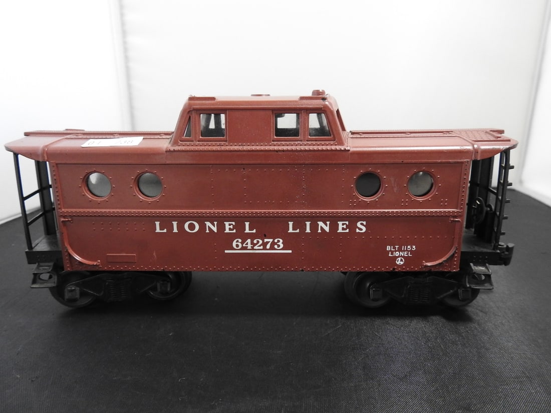 Lionel Lines No. 64273 Caboose: Lionel O gauge Lionel Lines No. 64273 caboose with brown body, porthole-style side windows, end platforms, black handrails, and BLT 1153 marking. Postwar-style, 1950s-era caboose design. Approx. 3.5