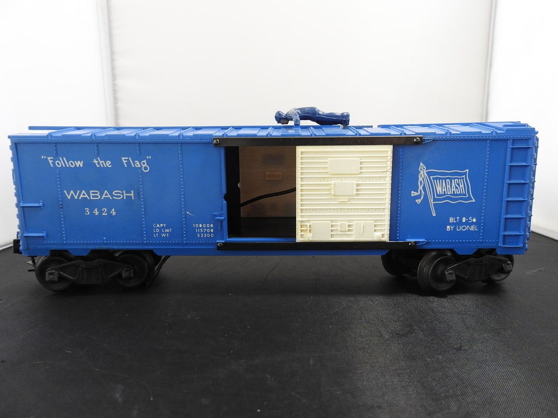 Lionel No. 3424 Wabash Operating Brakeman Boxcar: Lionel O gauge No. 3424 Wabash 'Follow the Flag' operating brakeman boxcar with blue body, white sliding door, roof figure, Wabash logo, and visible 3424-1 internal plate. Side lettering includes BLT
