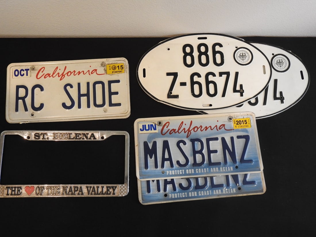 Seven-Piece Vintage License Plate Lot: Seven-piece vintage German and American license plate lot with one plate frame. All metal. Approx. 2 x 9 x 15 in.