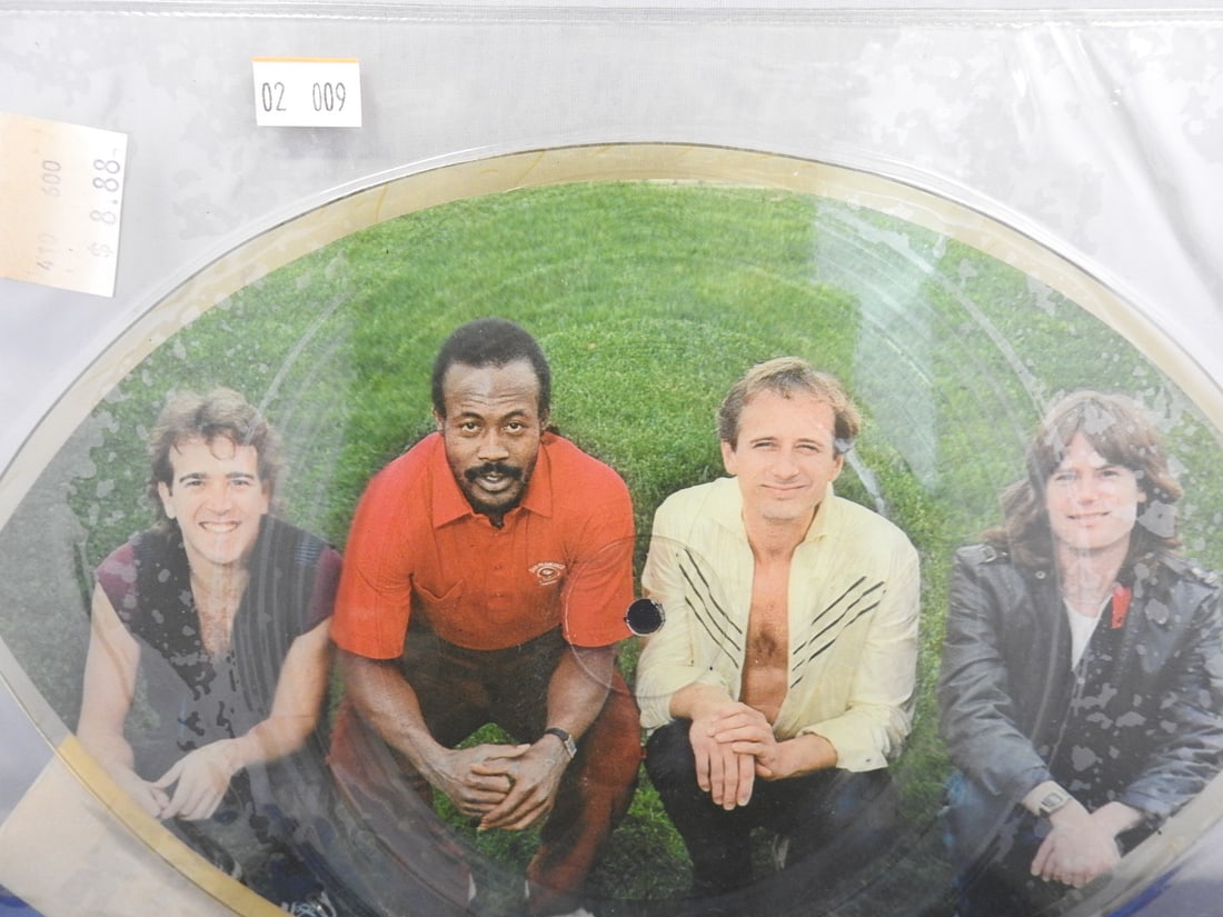 Man Machine All Alone in the Zone Football-Shaped Picture Disc: Man Machine All Alone in the Zone novelty football-shaped picture disc featuring a three-person photo image on the front and football graphic on the reverse. Original sticker remains on the clear slee