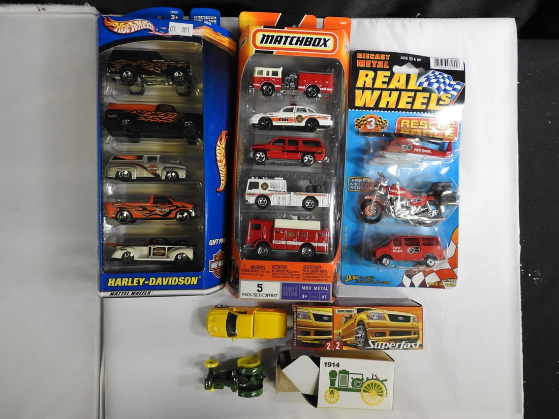 Hot Wheels, Matchbox and Real Wheels Emergency Vehicle Lot: Mixed group comprising Hot Wheels Harley-Davidson five-pack, Matchbox emergency five-pack, Real Wheels three-piece rescue set and loose yellow pickup and vintage tractor models.