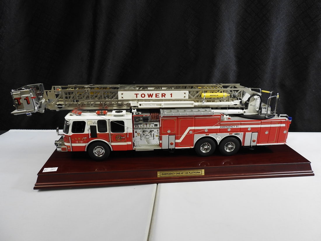 Precision Models Tower 1 Aerial Ladder Fire Truck: Large green Tower 1 aerial ladder fire truck model on a wood display base, marked Emergency 911. Underside label identifies a handcrafted Precision Models example.