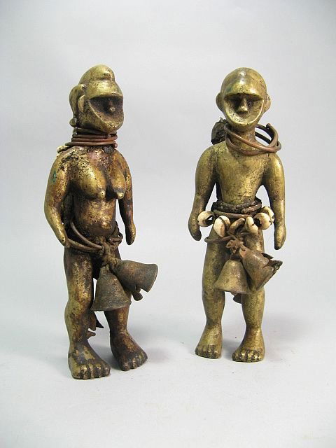 African Tribal Fetish Figures, Bronze Brass Copper: This male-female pair are based upon a traditional theme of royals, ancestors, life and fertility. West African, adorned with copper rings, cowrie shells, bells and wrapped rope sacks encrusted in ear