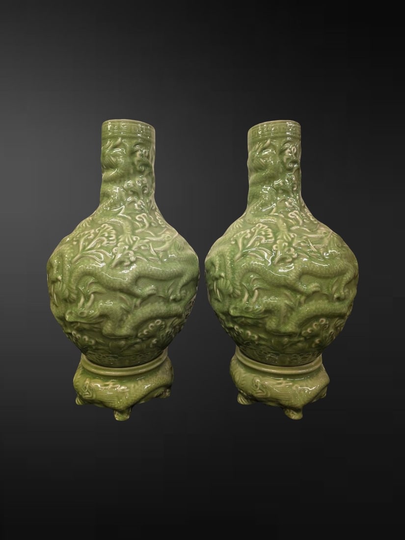 Pair of Large Chinese Longquan-Style Celadon ‘Dragon’ Bottle Vases on Stands: A striking pair of large bottle vases of globular form rising to a tall cylindrical neck, each boldly carved and moulded in relief with sinuous five-clawed dragons writhing amid ruyi cloud scrolls in 