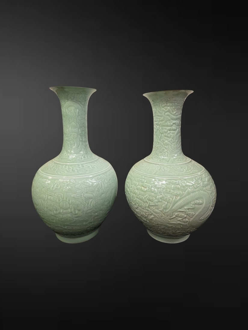 A Pair of Large Chinese Celadon-Glazed "Dragon" Bottle Vases: A handsome and substantial pair of Chinese celadon-glazed bottle vases, each of shangping form with a globular body rising to a tall slender neck terminating in a flared trumpet mouth. The bodies are 