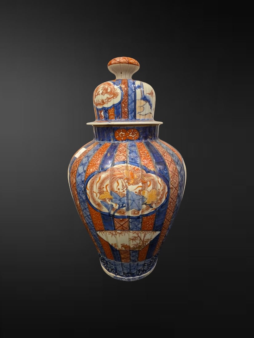A Japanese Imari Ribbed Baluster Jar and Cover with Ho-o Bird: A handsome Japanese Imari jar and cover of generous baluster form, the body moulded with vertical ribbing and decorated in the classic Imari palette of underglaze blue, iron-red and gilt. The ovoid bo
