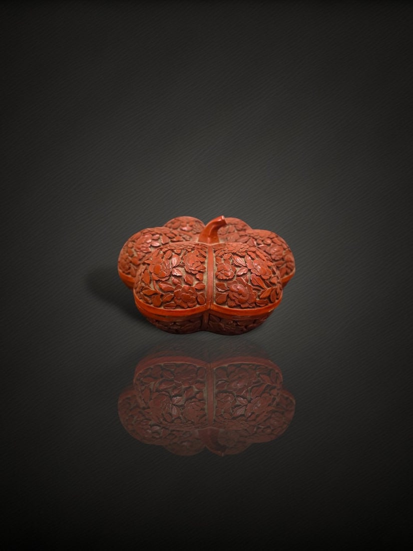 A Chinese Carved Cinnabar Lacquer 'Peony' Lobed Box and Cover: A carved cinnabar lacquer box and cover of five-lobed, flower- or melon-form shape, carved overall in relief with dense peony blossoms, buds and leafy foliage reserved against a buff-toned incised gro
