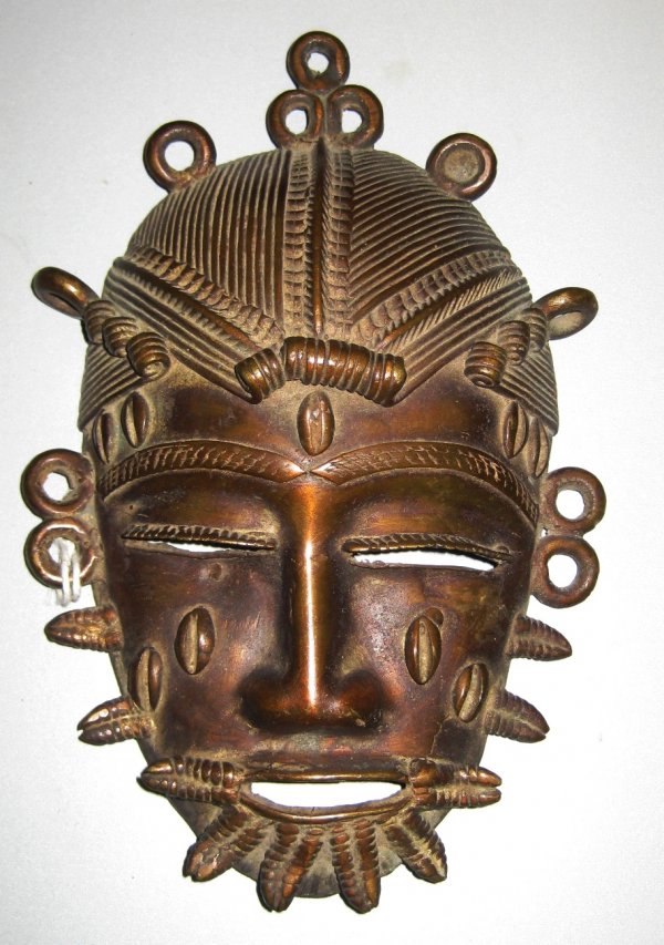 A BENIN BRONZE MINIATURE MASK HEAD, stylized stria: A BENIN BRONZE MINIATURE MASK HEAD, stylized striated coif, pierced earrings, and braided beard, height 8", width 5 1/2"