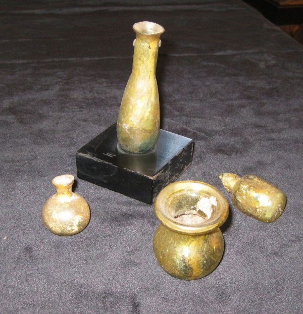 FOUR ANCIENT IRIDESCENT GLASS VESSELS, consisting: FOUR ANCIENT IRIDESCENT GLASS VESSELS, consisting of two small vials, height 2 " (one damaged neck), one small jar, height 1 1/4" and one vial on a stand, height 3 1/2"