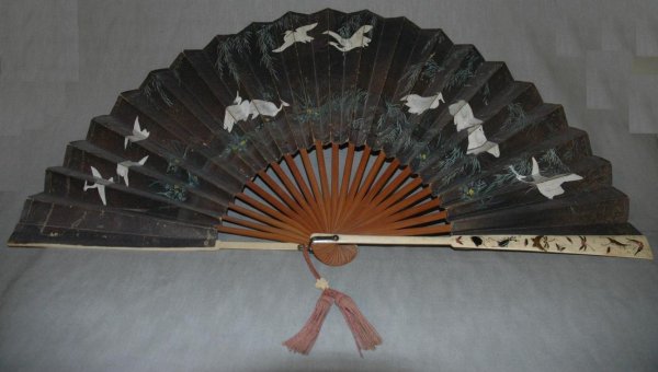 A CHINESE DOUBLE SIDED PAINTED PAPER FAN WITH INLA: A CHINESE DOUBLE SIDED PAINTED PAPER FAN WITH INLAID IVORY GUARDSTICKS one side painted with cranes on a black ground and the other side flowers and birds on a red ground, guardsticks inlaid with inse