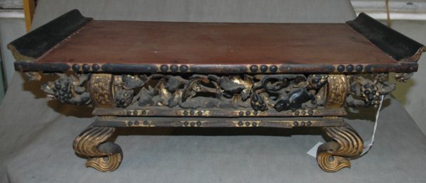 A SOUTHEAST ASIAN CARVED WOOD ALTAR TABLE the top : A SOUTHEAST ASIAN CARVED WOOD ALTAR TABLE the top with raised ends, above pierced frieze carved fruit and animals on S-scroll legs. height 9", length 25"