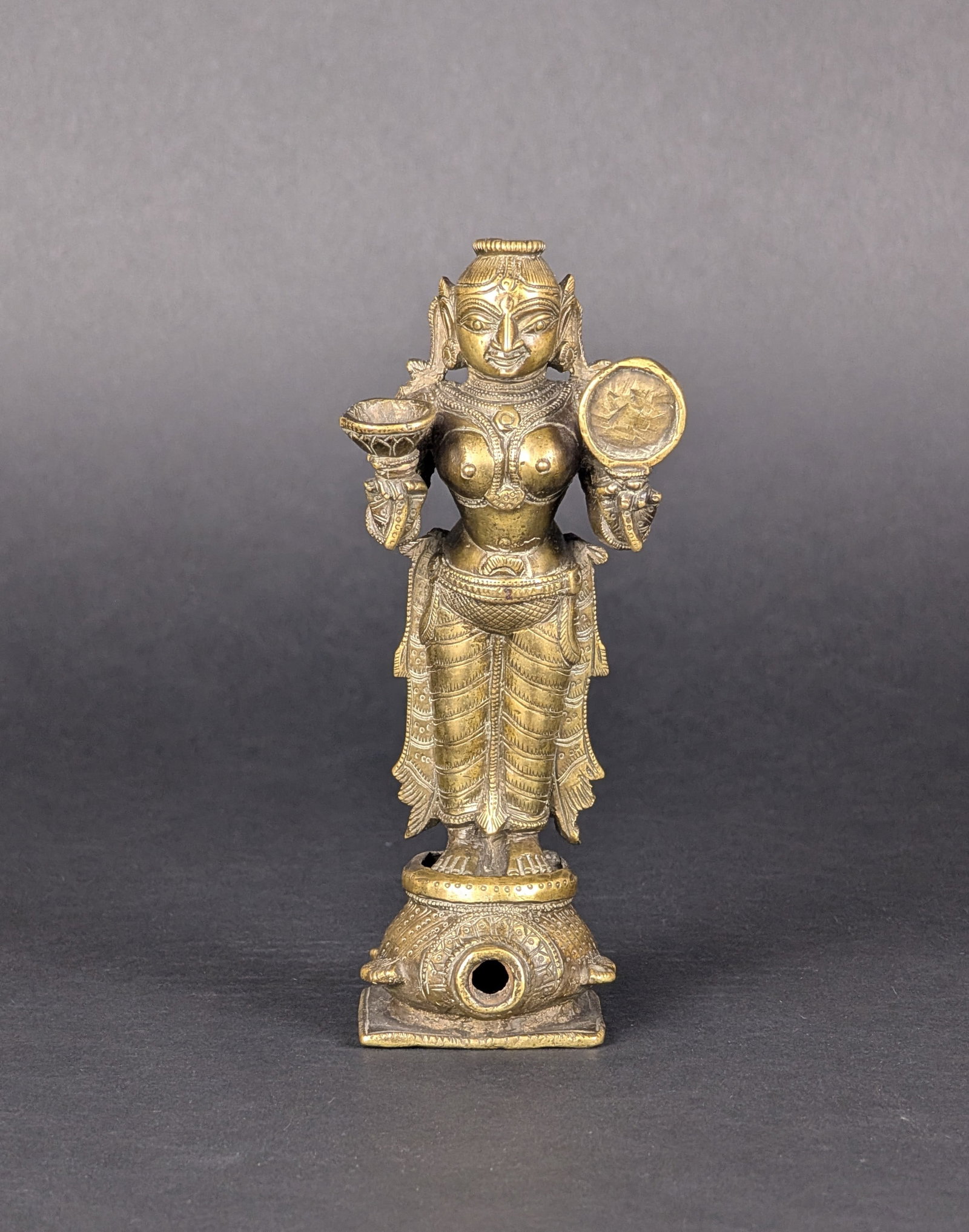 Goddess on a Turtle: The interpretation of this bronze varies, from the Yamuna Goddess to a container of cosmetics. As Yamuna, she is the personification of the sacred river. Yamuna stands on a tortoise. As Surasundari,