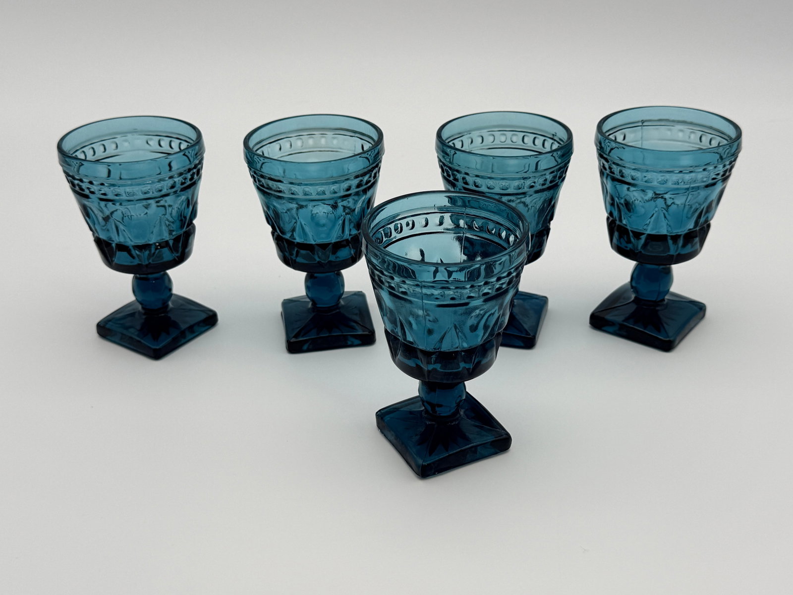 Vintage Blue Pressed Glass Goblets Set: Set of 5 vintage blue pressed glass goblets with square pedestal bases.