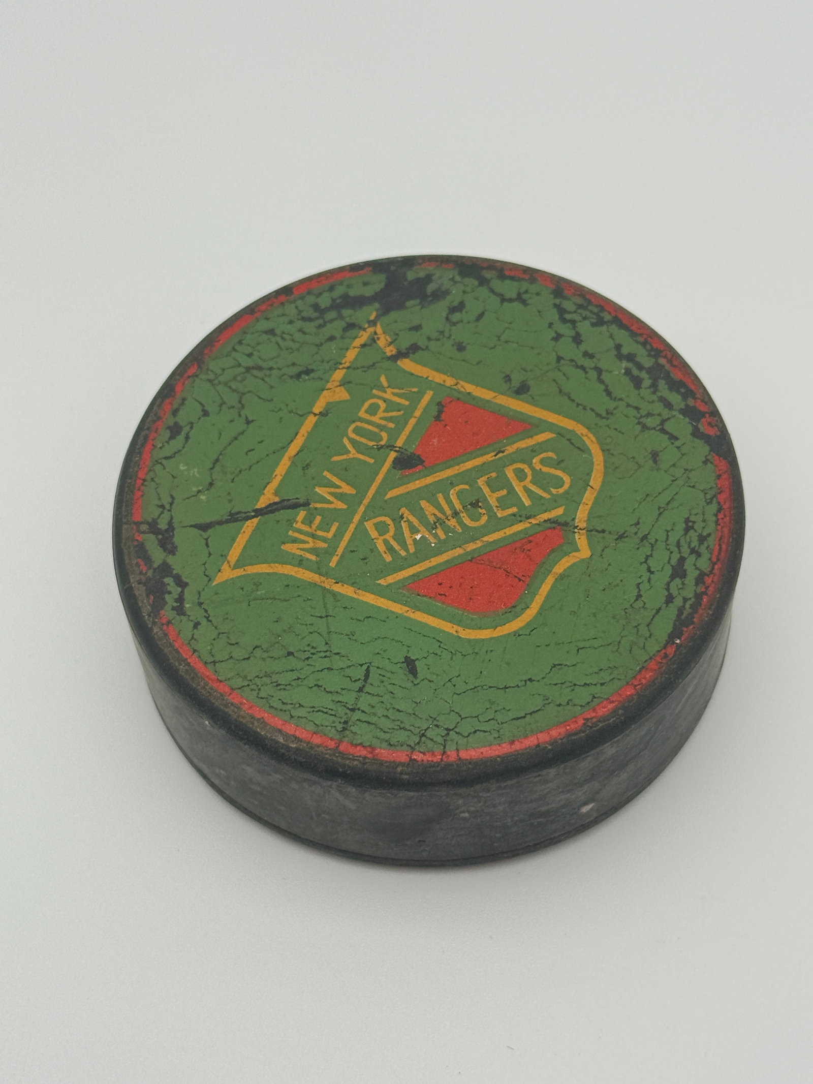 Vintage New York Rangers Hockey Puck: Vintage New York Rangers black hockey puck with worn logo and age-related wear.