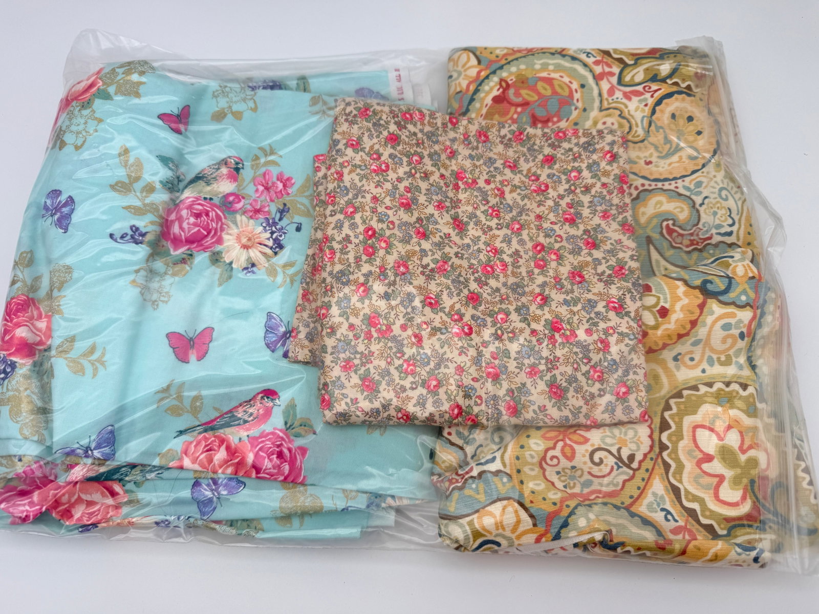 Fabric Remnant Lot: Mixed fabric pieces in assorted floral and paisley prints. Age and fiber unverified.