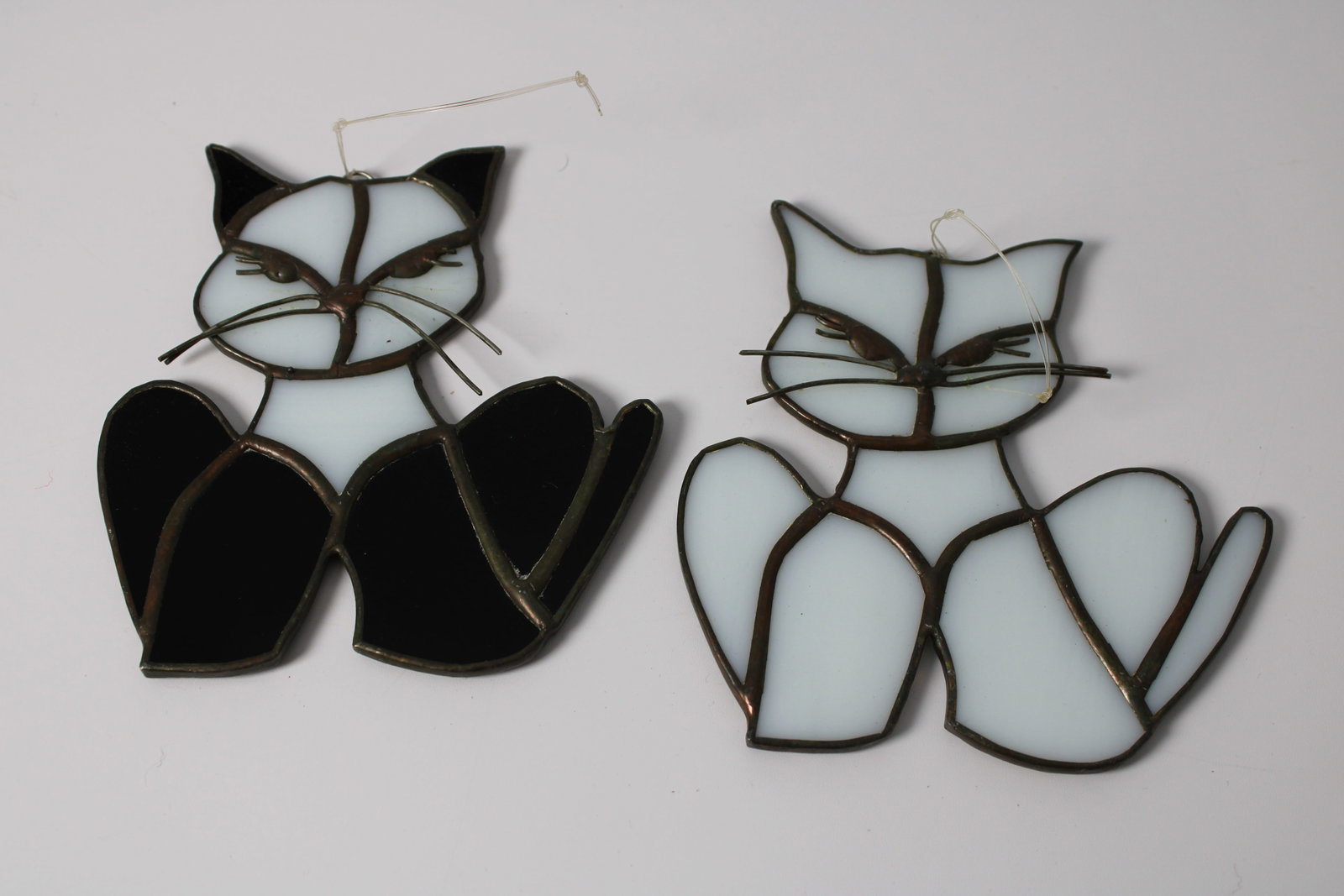 Pair of Stained Glass Cat Suncatchers: Two black and white stained glass cat ornaments with metal whiskers and hanging loops. Each measures approximately 4.5 x 3.75 inches