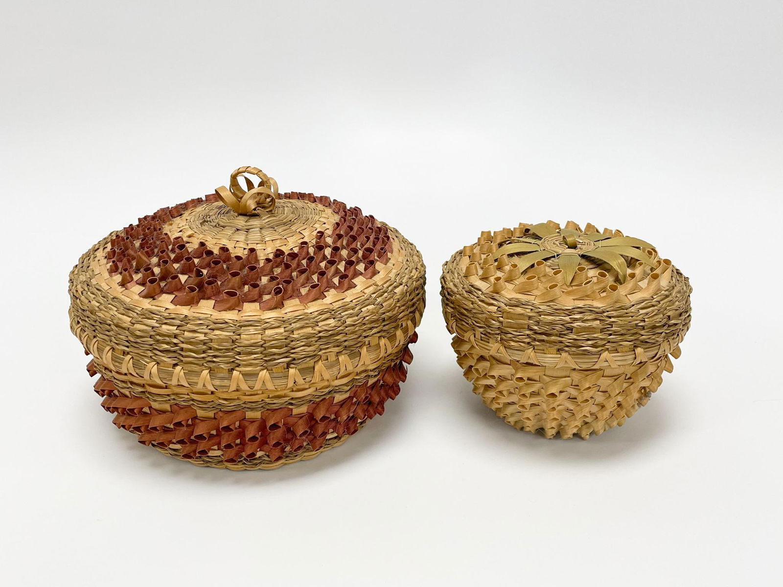 2 Mohawk Sweet Grass Covered Sewing Baskets: both in excellent condition. Made on the Akwesasne Indian Reserve in New York State. 8" in diameter and 5 1/2" in diameter. From the Estate of Carlton Stickney, County & Town Historian and Lifetime Co