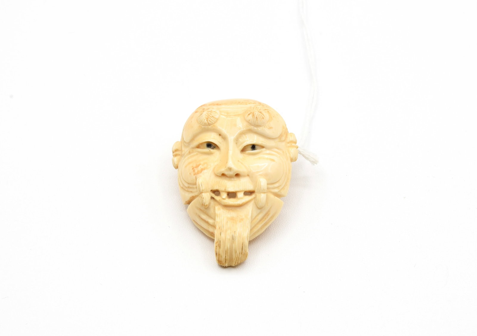 Signed Okina Mask Netsuke Carved Antique Bone: Signed and Hand-carved bone Okina mask Japanese netsuke. Himotoshi and signature on back, beautiful detailed. Measures 1 7/8"