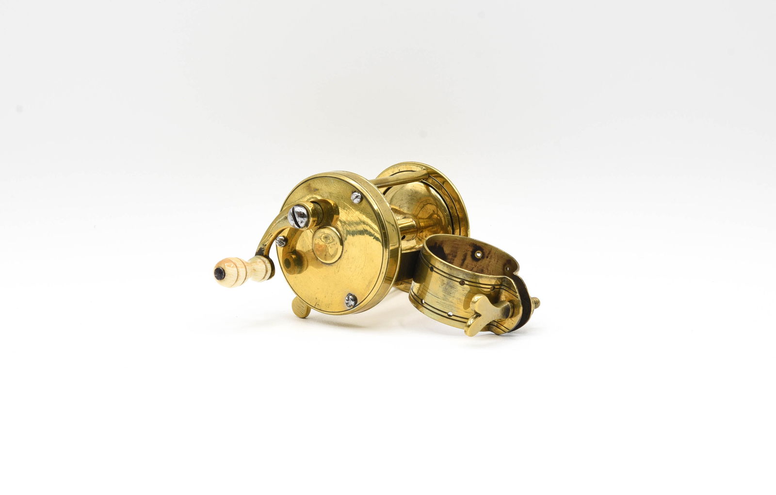 Unmarked Brass Multiplying Clamp Reel: 1 3/4" diameter, 1 3/8" wide spool, with a clamp that features holes to allow the reel to be lashed to a rod, rim mounted spool stop, bone handle grasp fitted to a curved crank handle, working stop sw