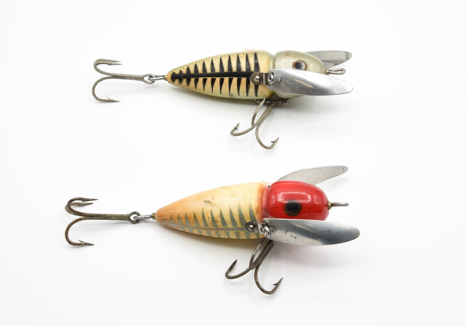 Heddon Musky Crazy Crawlers: Both finished in a shore pattern with a patent number marked wing. Includes a scarce silver shore, no black head accents, belly stencil, Ex-/Ex, and red and white shore, VG/VG+ condition due to wear, 
