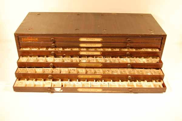 6 Drawer Metal Wrist Watch Crystal Cabinet: filled with new old stock. 23" x 7" x 9 1/2". Provenance: from an estate in Middlebury, VT along with a collection of clock, watchmakers and jewelers tools; numerous pocket watches & parts; early pock
