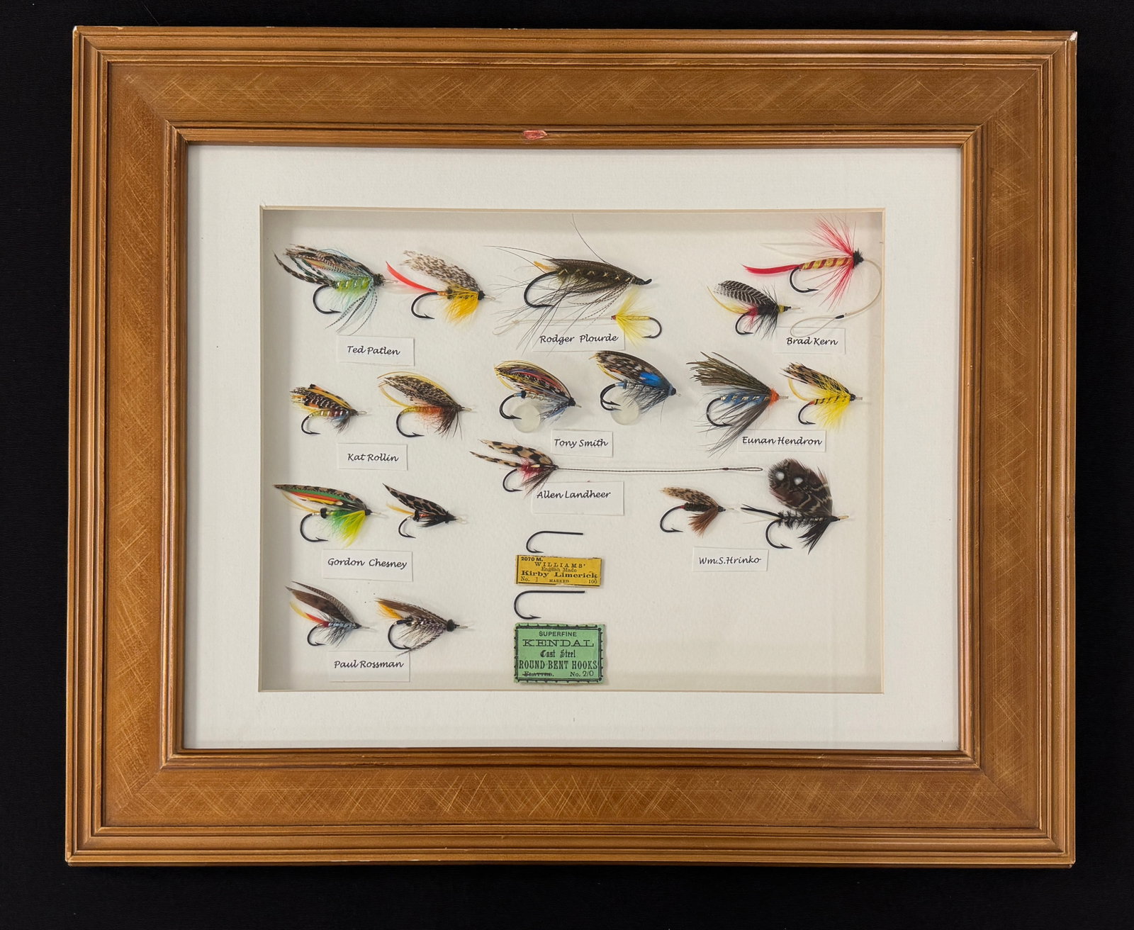 Bill Hrinko Owned Fly Display: 19 flies gifted to their fellow tyer William "Bill" Hrinko. Mounted in a 17 1/2" x 14 1/2" wooden shadow-box frame, the flies are represented by the tyer's name underneath, and all but one has signed