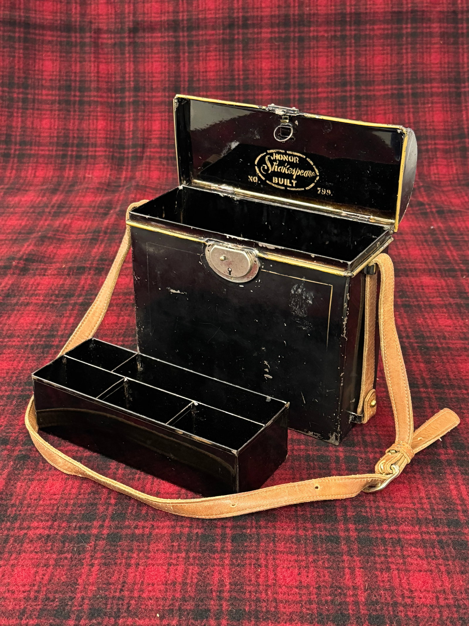 Early Shakespeare Tackle Box: Scarce early box in black japanned finish with original hardware and brass carrying handle, standing 9" tall and 9" wide. Including "Shakespeare Honor Built No. 799" painted on the interior lid to the