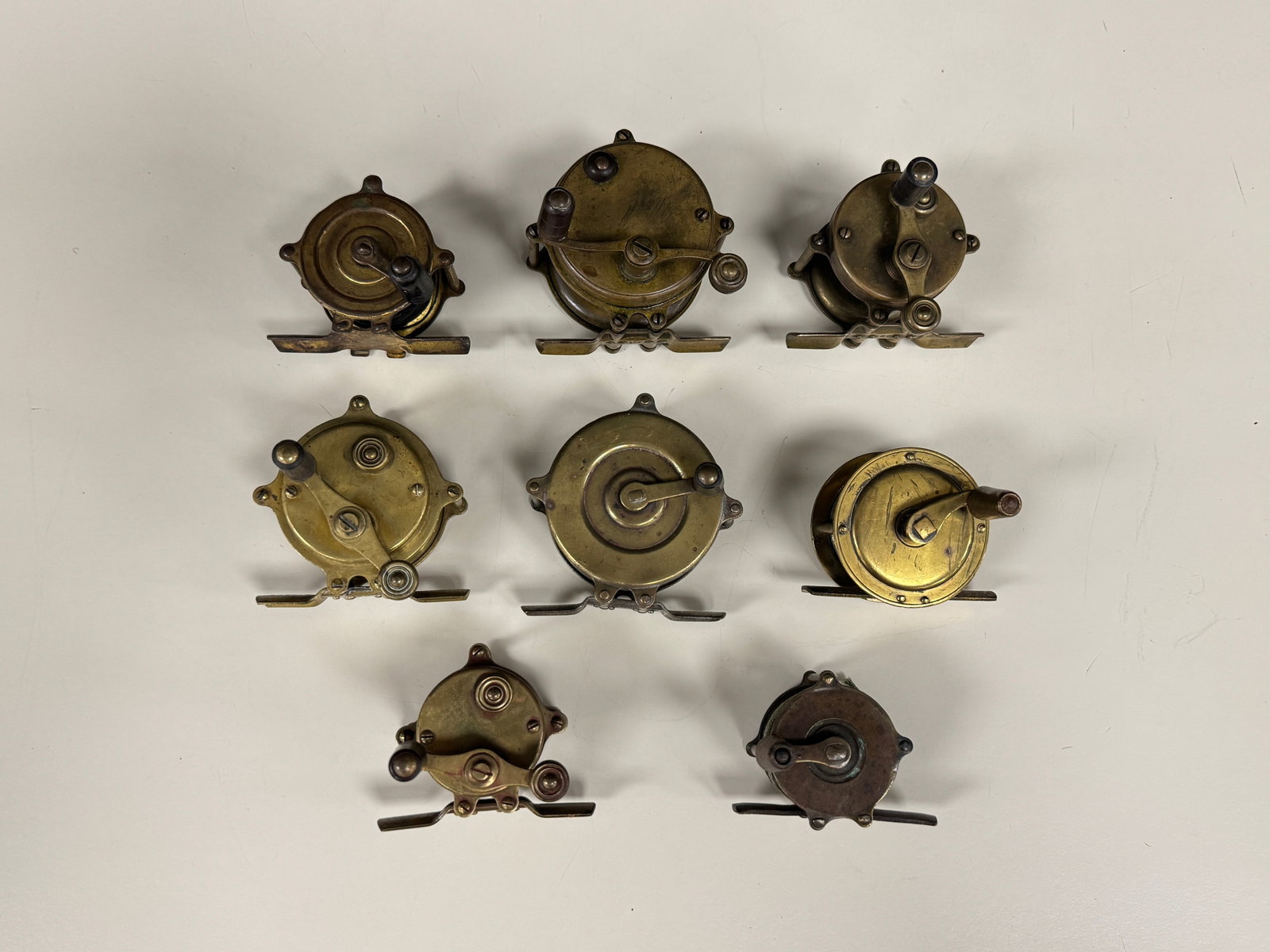 8 Vintage Brass Trout Reels: 7 are raised pillars. Range in size from 1.5" to 2.25" diameter.