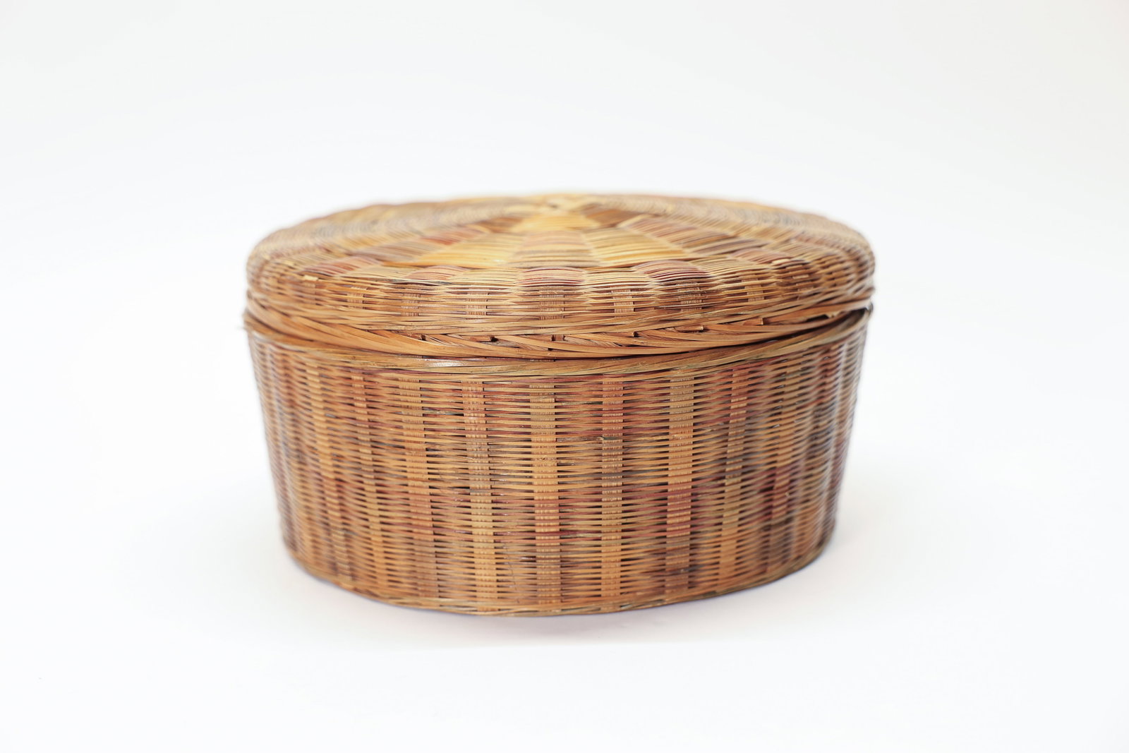 Lidded Woven Basket Multicolor Starburst: Beautiful lidded round woven basket featuring an intricate radiating starburst weave pattern on the domed lid, accented with multicolored strands in deep red, forest green, and black woven throughout 