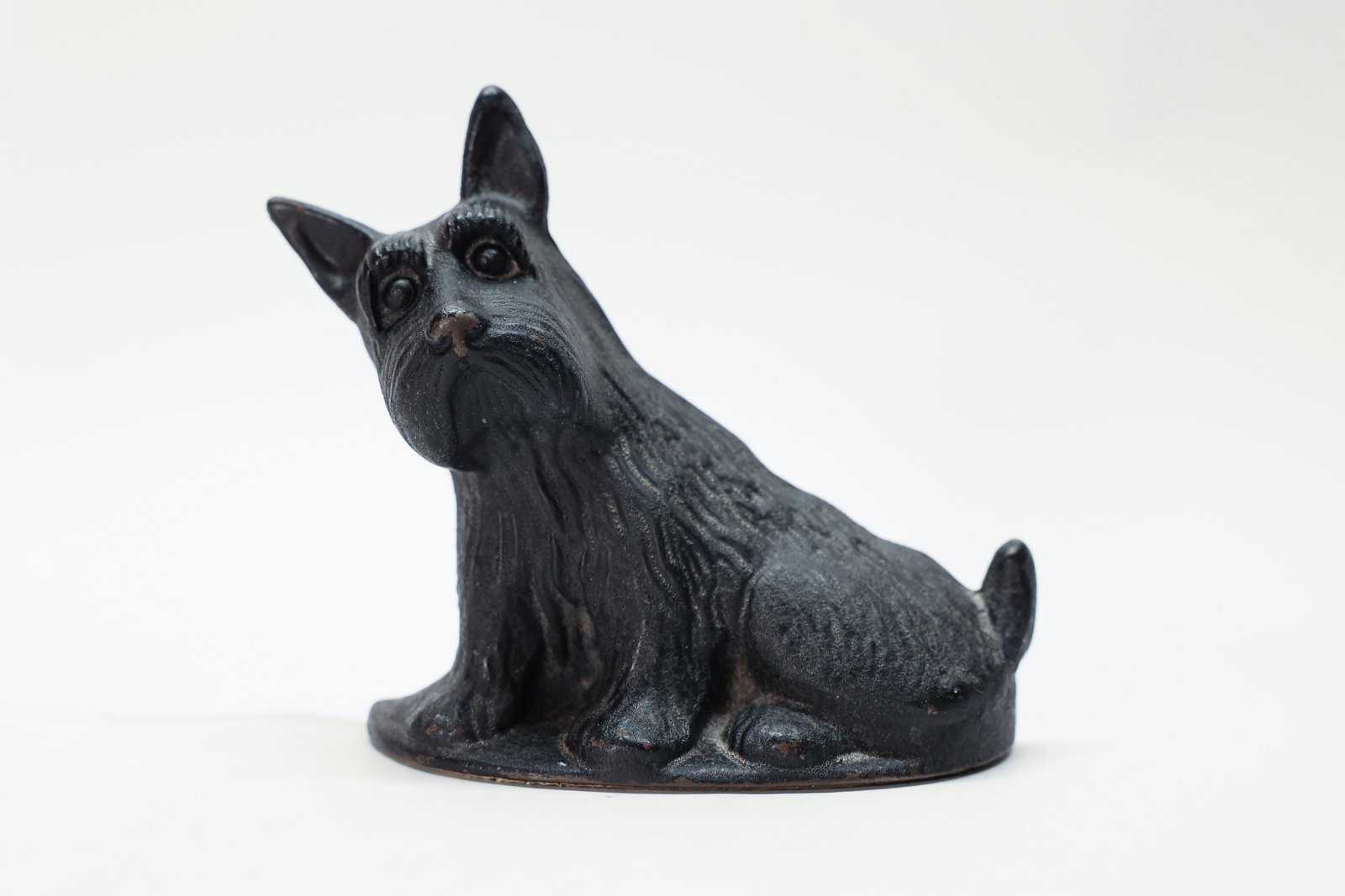 Antique Cast Iron Scottie Dog Bookend: 1930s. 5 1/2 x 2".A charming antique cast iron Scottish Terrier bookend, depicting the beloved "Scottie" dog seated and alert, with perky pointed ears, a bushy beard, and expressive glass or painted