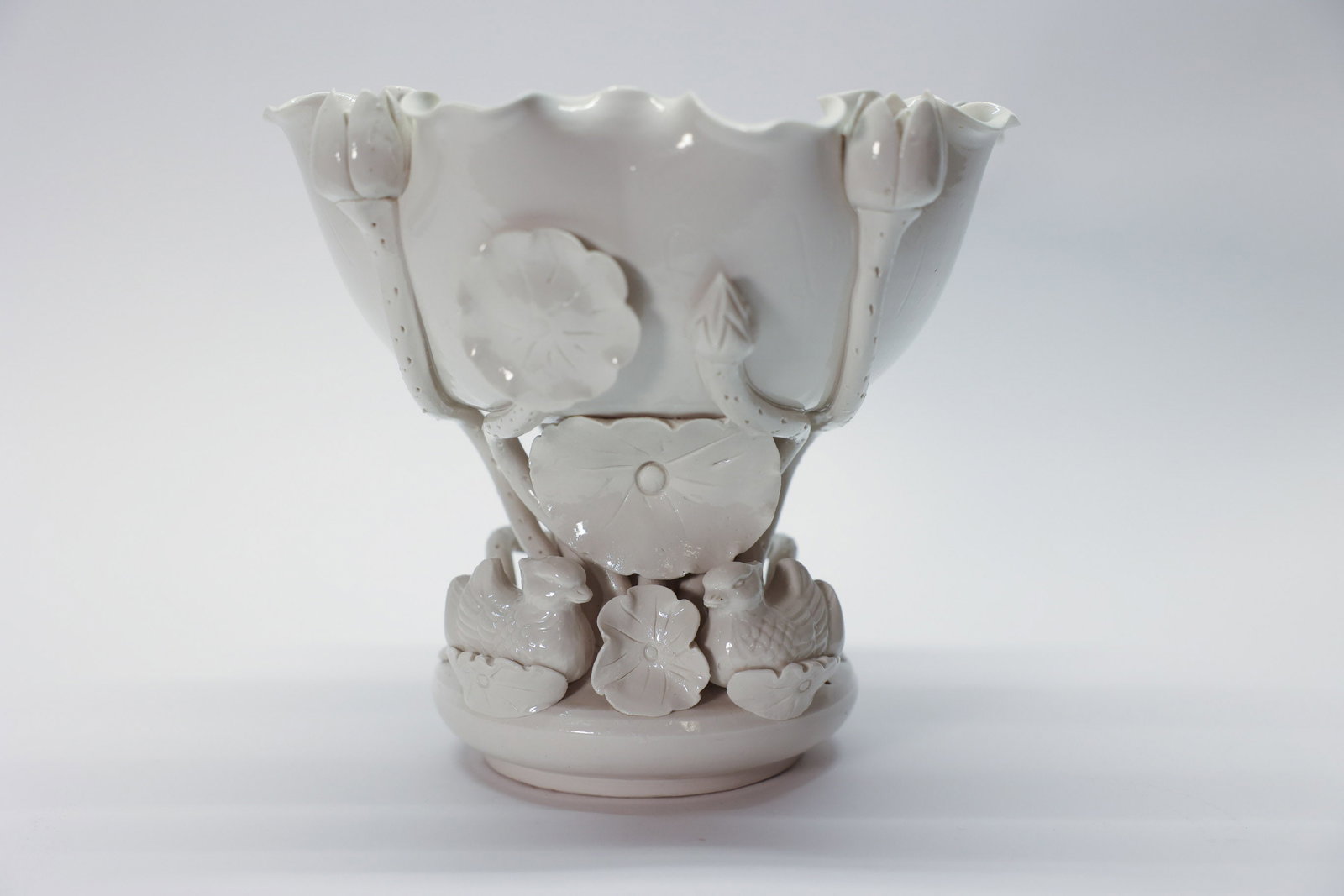 Dehua White Porcelain Compote Blanc de Chine: A beautifully sculptural antique Dehua (Chinese blanc de chine) white porcelain compote, featuring a scalloped, ruffled-edge bowl raised on an elaborate figural stem. The base is richly decorated with