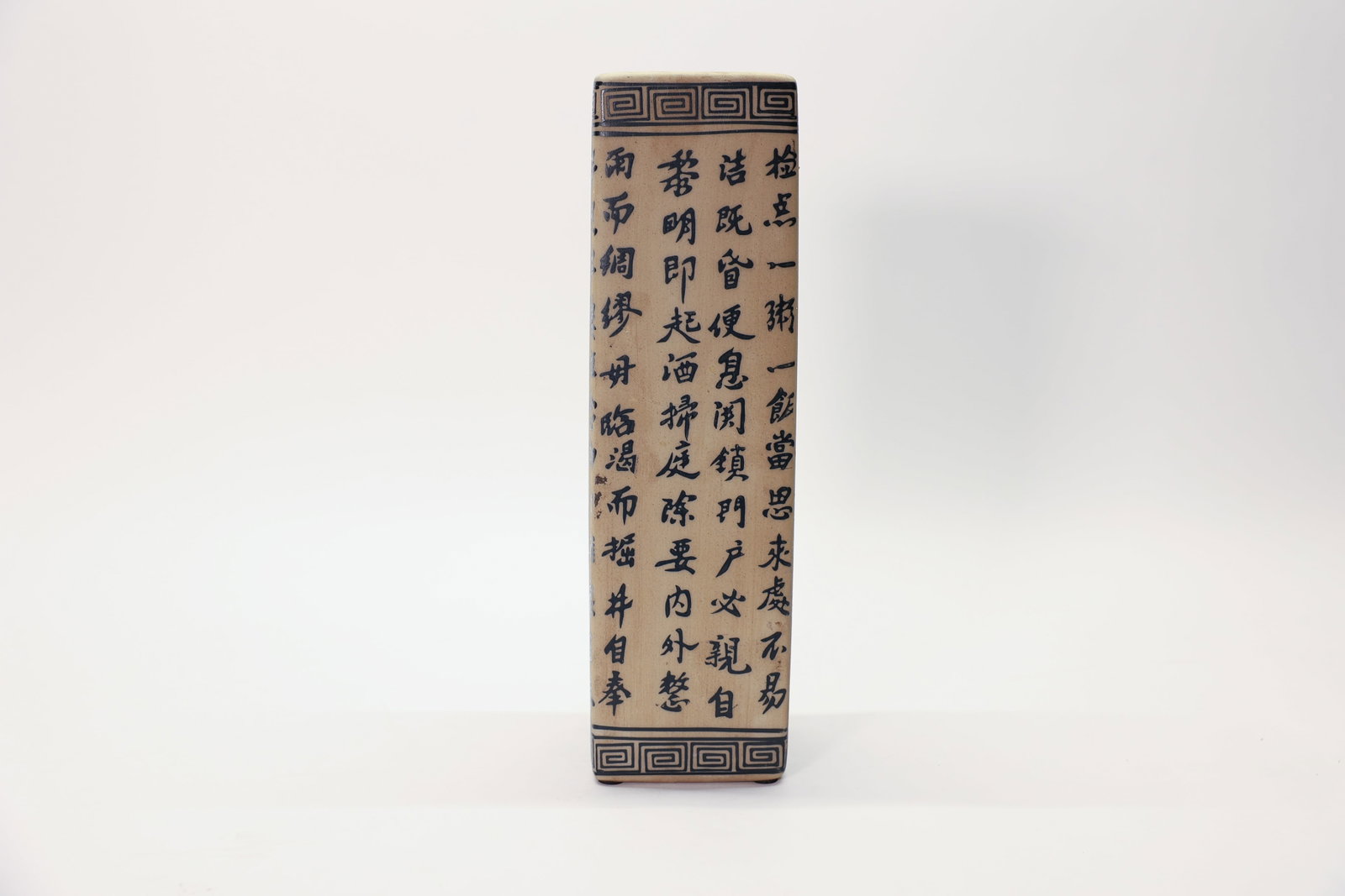 Chinese Ceramic Calligraphy Vase 12.5": A striking square-form Chinese ceramic vase, measuring 3.5" wide by 12.5" tall, featuring vertical columns of hand-painted black calligraphy script covering the body, bordered by classic Greek