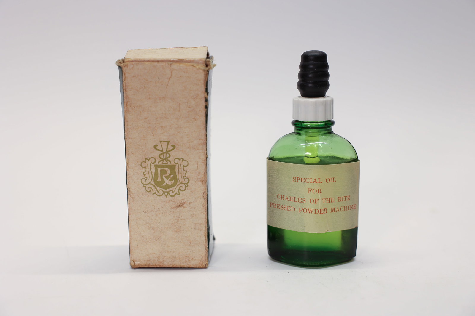 Vintage Charles of the Ritz Special Oil Bottle: 4.5" tallA wonderful vintage advertising bottle for "Special Oil for Charles of the Ritz Pressed Powder Machine," presented in a charming green glass bottle with its original paper label and black rib
