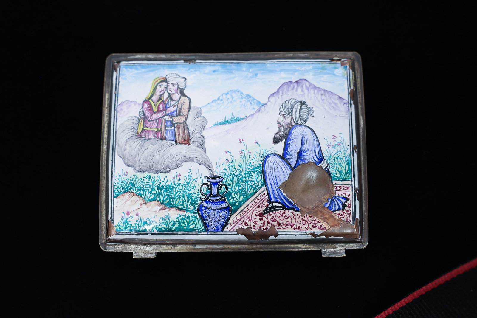 Enamel & Silver Cigarette Case on Copper, Mughal: Condition Report:The enamel shows losses and chipping at several corners and edges of the lid, most notably at the front right corner and along parts of the border, exposing the copper base beneath.
