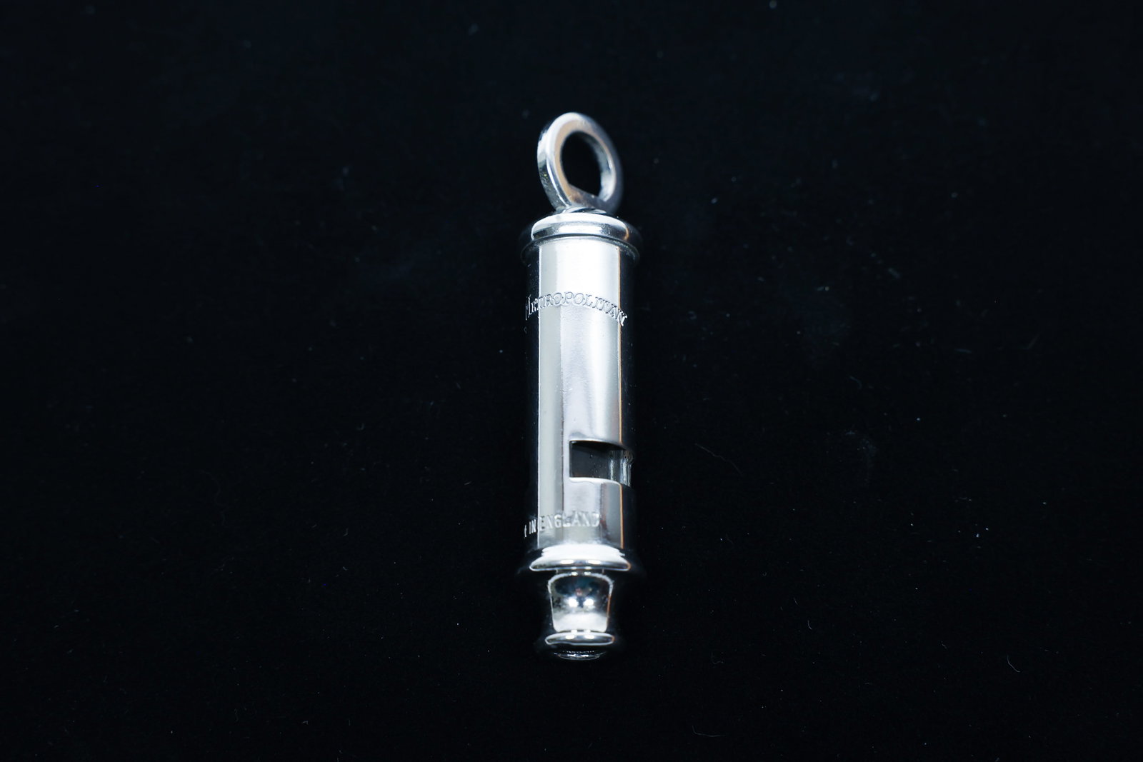 "The Metropolitan" Chrome Whistle, England: Chrome-plated brass police-style whistle engraved "The Metropolitan" with "Made in England" stamped near the mouthpiece. Suspension loop at top for a lanyard or chain.Dimensions: W: 0.75", L: 3.25"