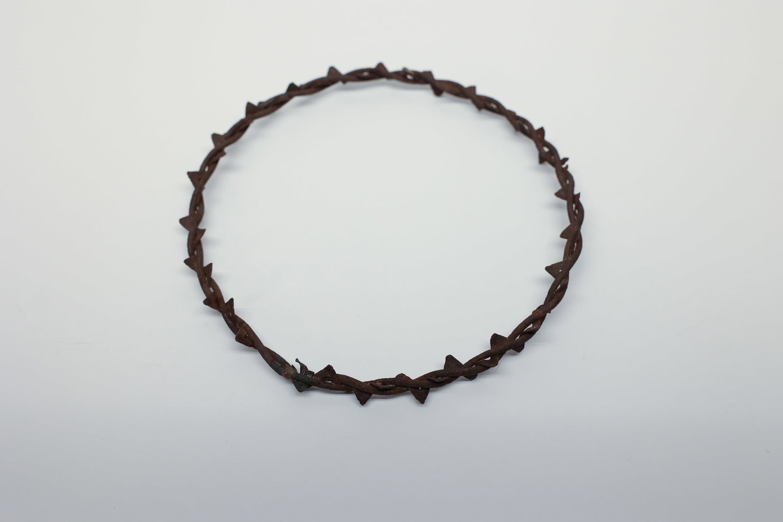 Antique Wrought Iron Crown of Thorns: A circular "crown of thorns" form hand-fashioned from twisted wrought iron wire, with sharp barb-like points spaced evenly around the ring, echoing the traditional Christian iconography of the crown o
